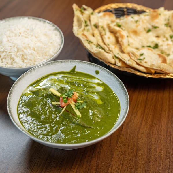 Palak Paneer with rice and naan bread on a wooden table.